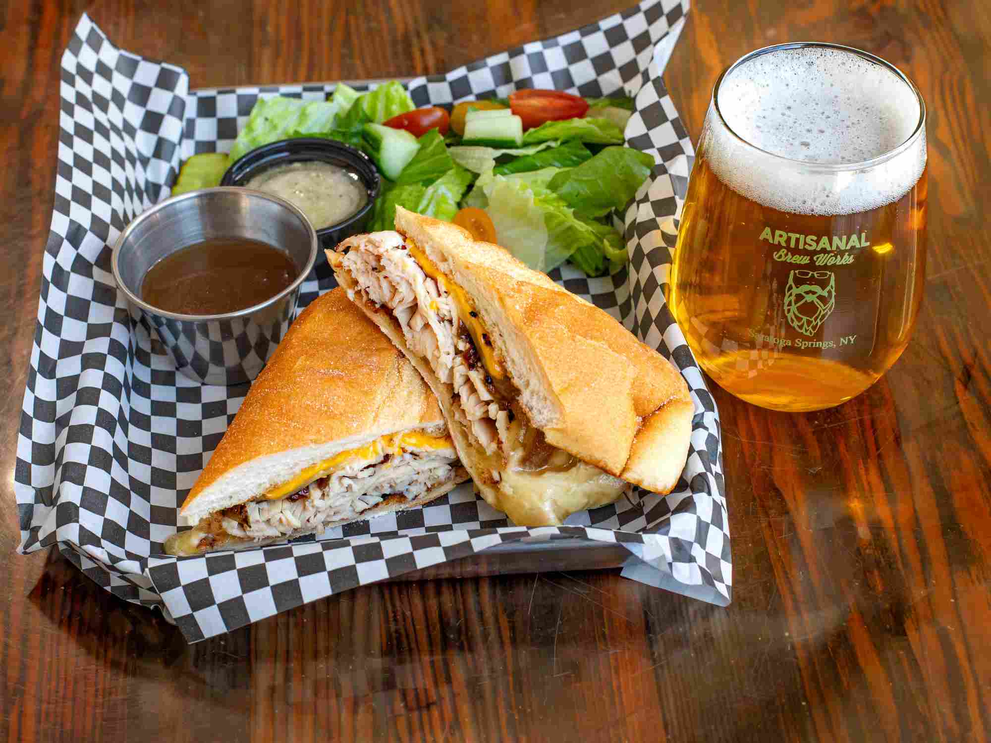 Turkey dip sandwich with grilled onions, cheddar, American cheese, and garlic butter roll with au jus at a Saratoga Springs restaurant