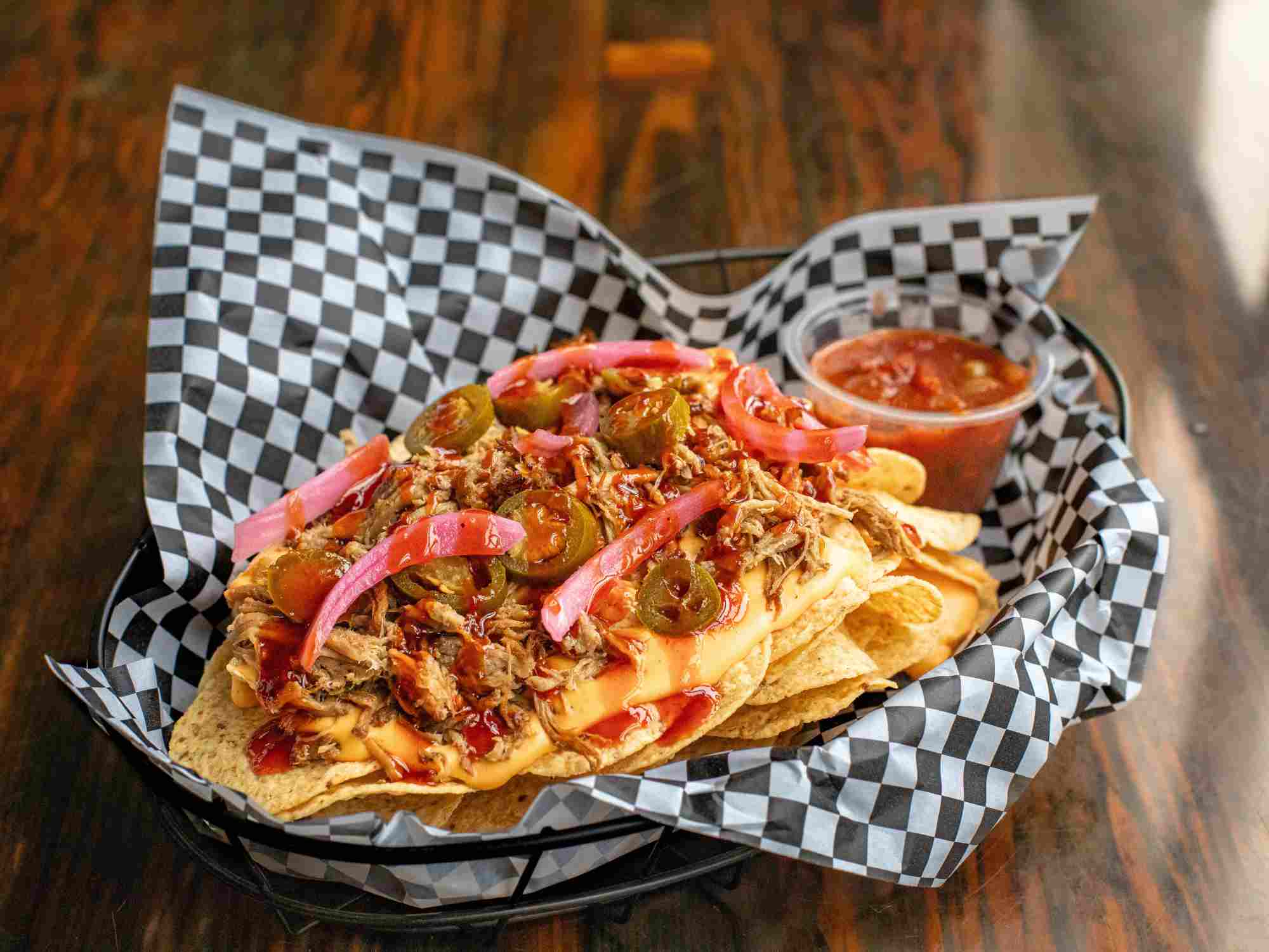 Nachos with pulled pork, Maui sauce, beer cheese, pickled onions, and jalapeños from the Artisanal Brew Works restaurant menu in Saratoga Springs