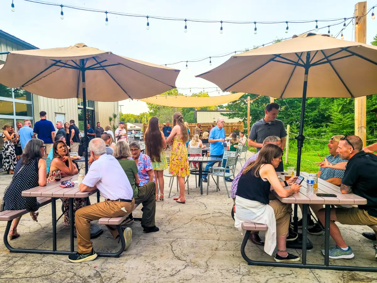 Outdoor patio dining at Nature’s Edge Terrace at Artisanal Brew Works restaurant in Saratoga Springs with guests enjoying food and drinks under umbrellas